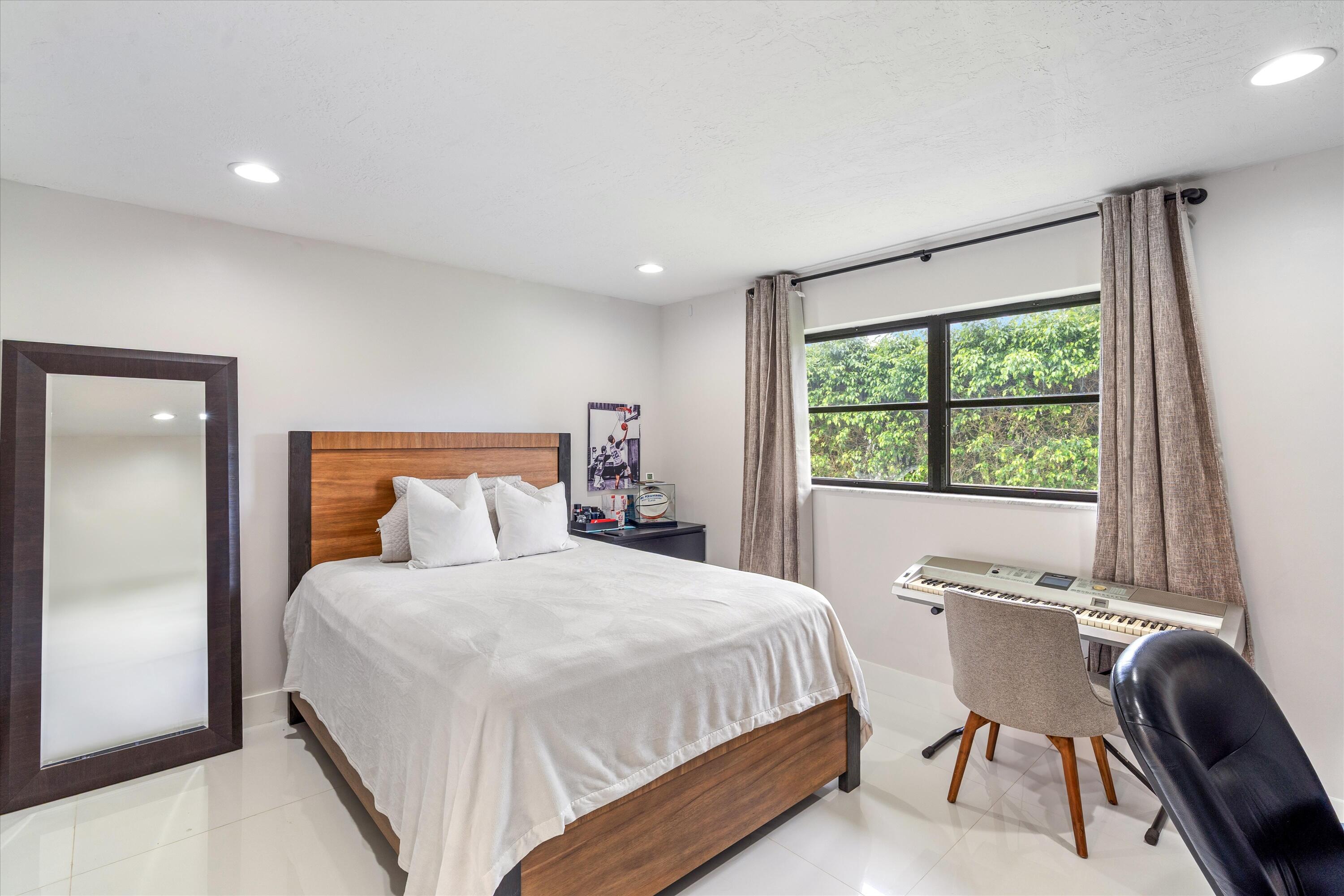 516 Muirfield Drive Atlantis, FL 33462 - Photo 23 of 43 a bedroom with a bed and a chair with outer view