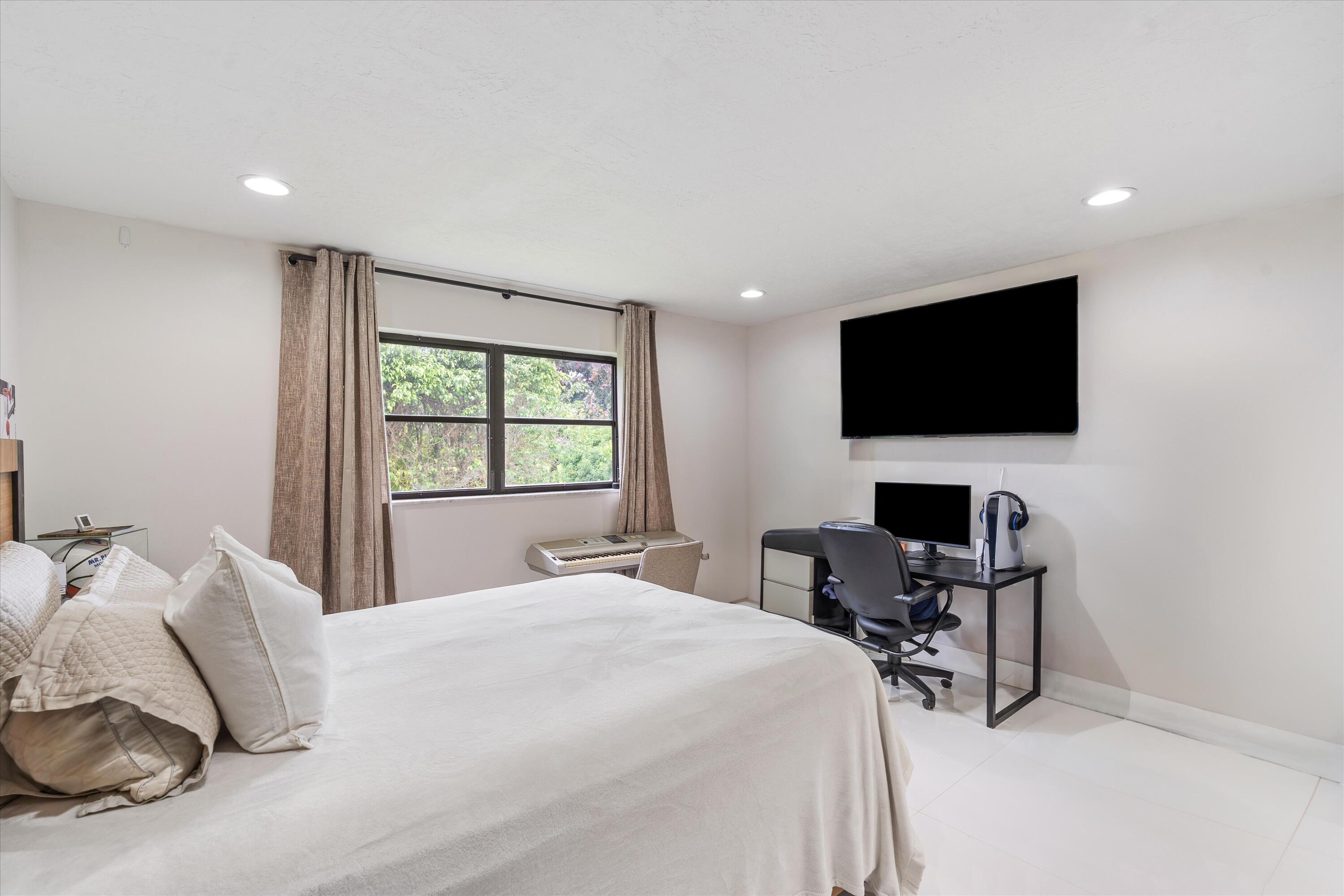 516 Muirfield Drive Atlantis, FL 33462 - Photo 24 of 43 a bedroom with a bed and a flat screen tv