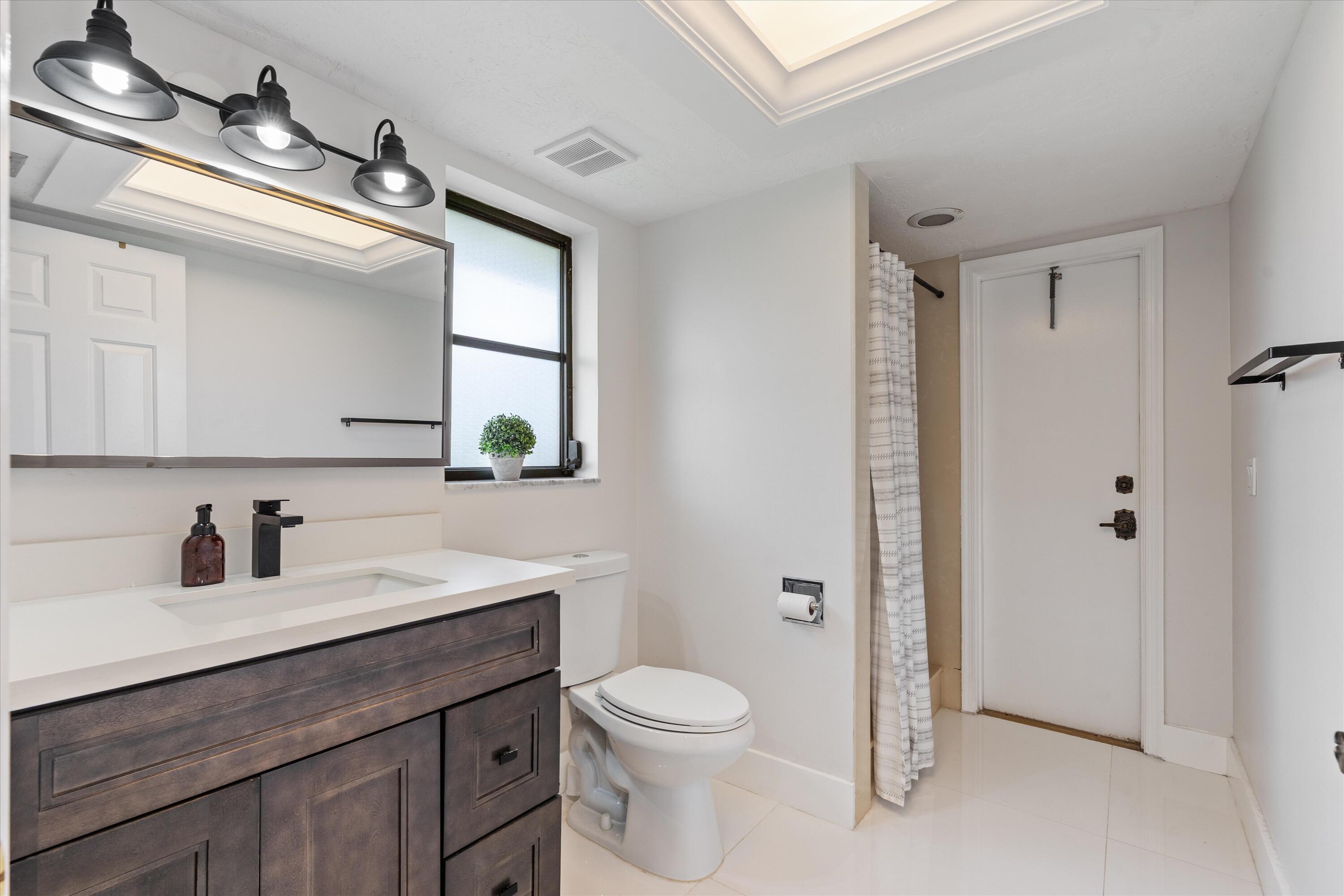 516 Muirfield Drive Atlantis, FL 33462 - Photo 25 of 43 a bathroom with a toilet a sink a mirror and a shower