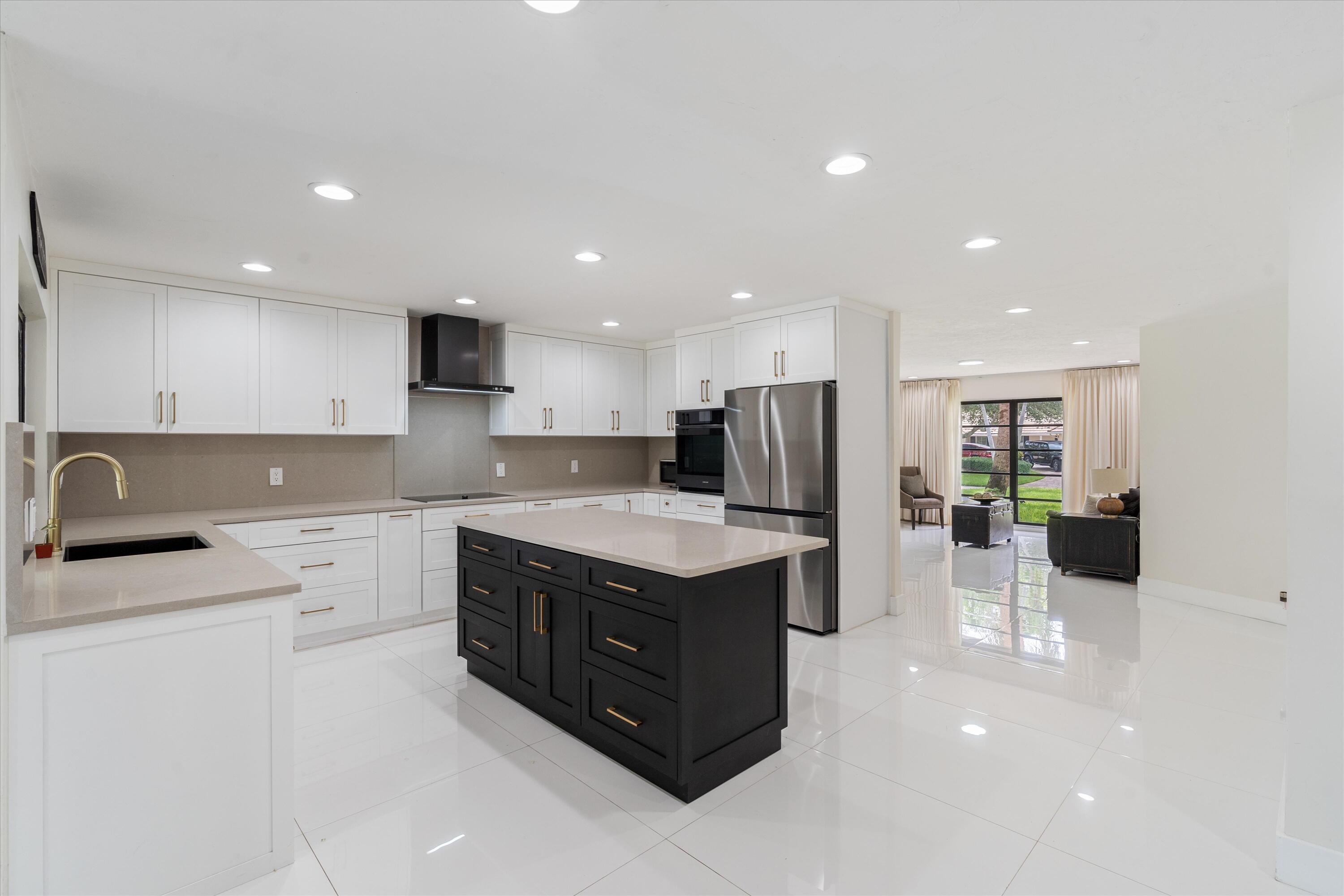 516 Muirfield Drive Atlantis, FL 33462 - Photo 9 of 43 a kitchen with a sink a stove a refrigerator and white cabinets
