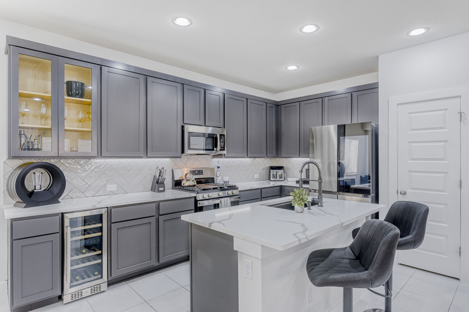 504 Spinnaker Loop Kyle, TX 78640 - Photo 4 of 17 Kitchen featuring light stone counters, gray cabinetry, a breakfast bar, beverage cooler, and stainless steel appliances