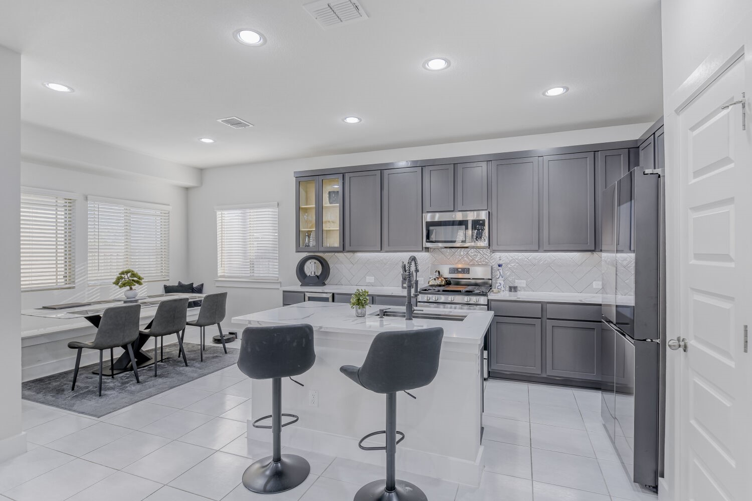504 Spinnaker Loop Kyle, TX 78640 - Photo 5 of 17 Kitchen featuring stainless steel appliances, gray cabinetry, light stone countertops, light tile patterned floors, and recessed lighting