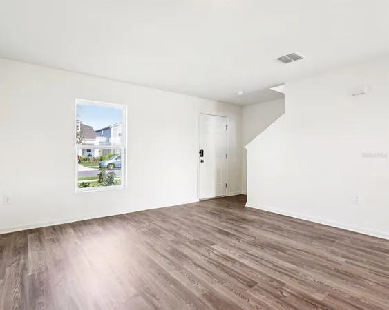 an empty room with wooden floor and windows