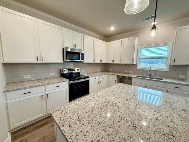 a kitchen with granite countertop a stove sink and cabinets