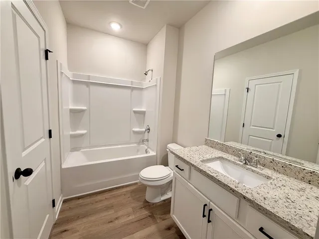 a bathroom with a granite countertop sink a toilet and shower