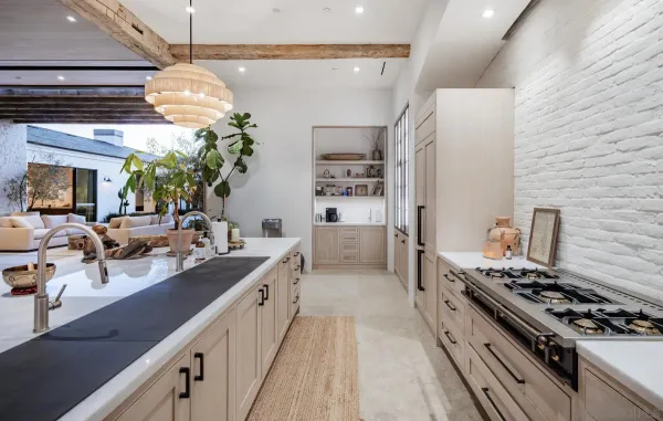 a kitchen with a counter space a chandelier and living room view