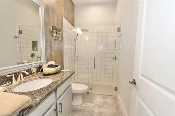 a bathroom with a granite countertop sink a toilet and shower