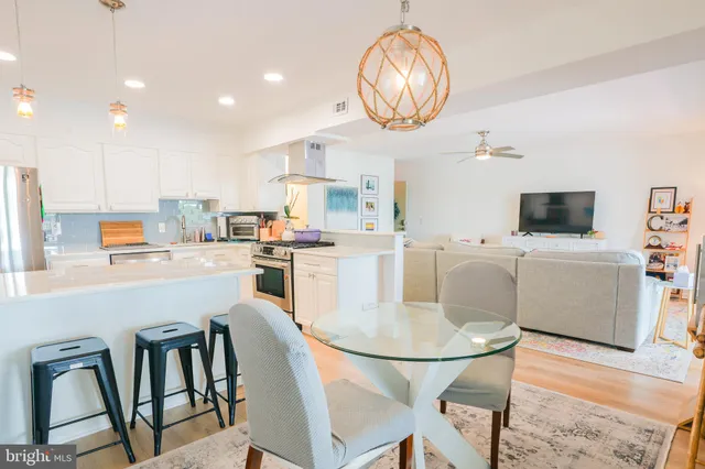 a kitchen with stainless steel appliances granite countertop a dining table chairs and white cabinets