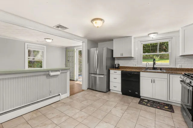 a kitchen with stainless steel appliances granite countertop a stove top oven a sink and a refrigerator