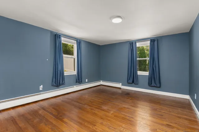 a view of an empty room with wooden floor and a kitchen
