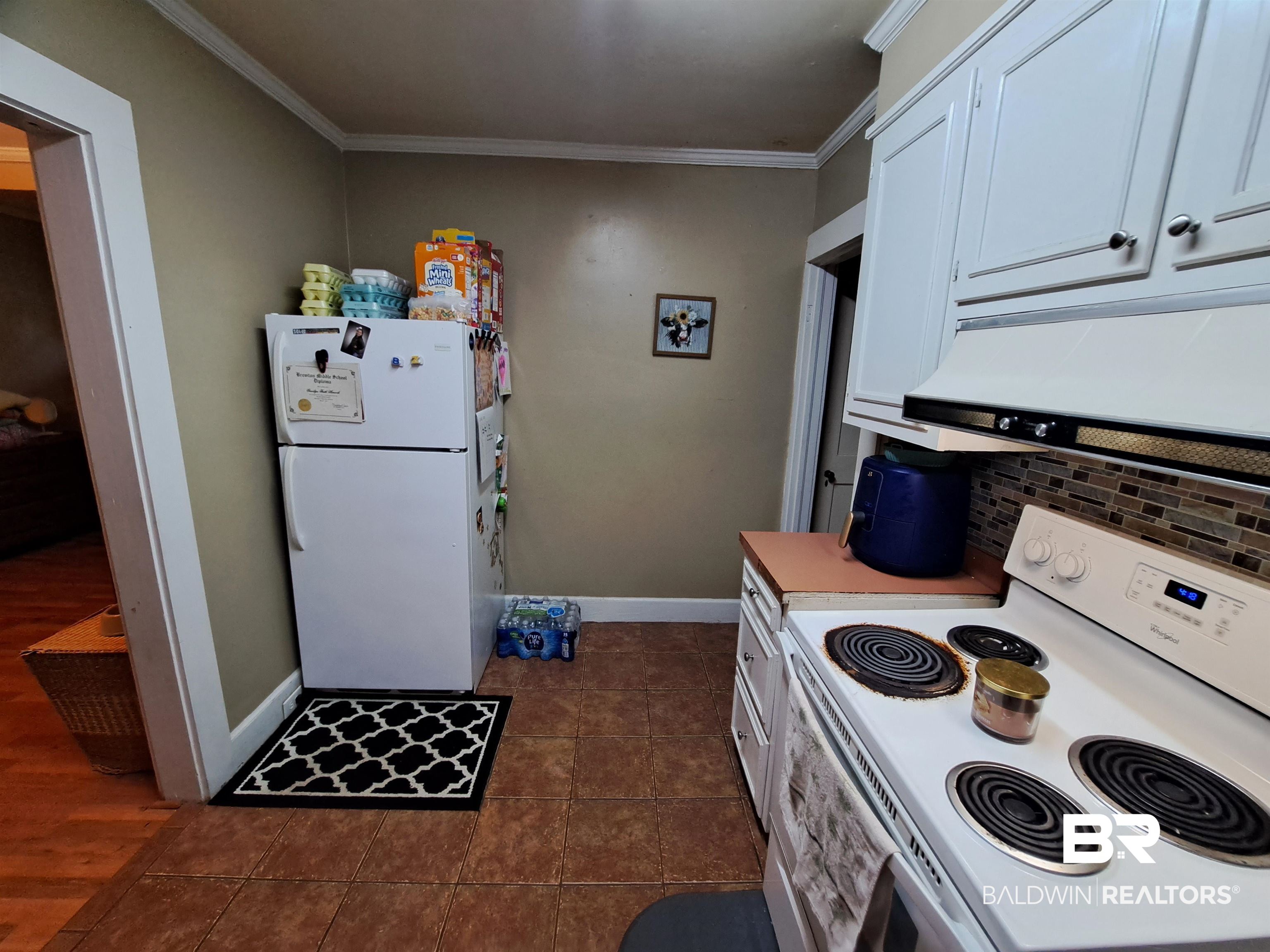309 Bellview Avenue Evergreen, AL 36401 - Photo 10 of 27 Kitchen featuring white appliances, ornamental molding, dark tile patterned floors, tasteful backsplash, and white cabinets