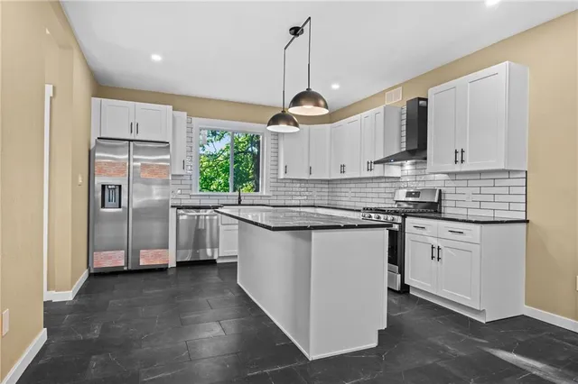 a kitchen with stainless steel appliances granite countertop a sink a stove and a wooden floors