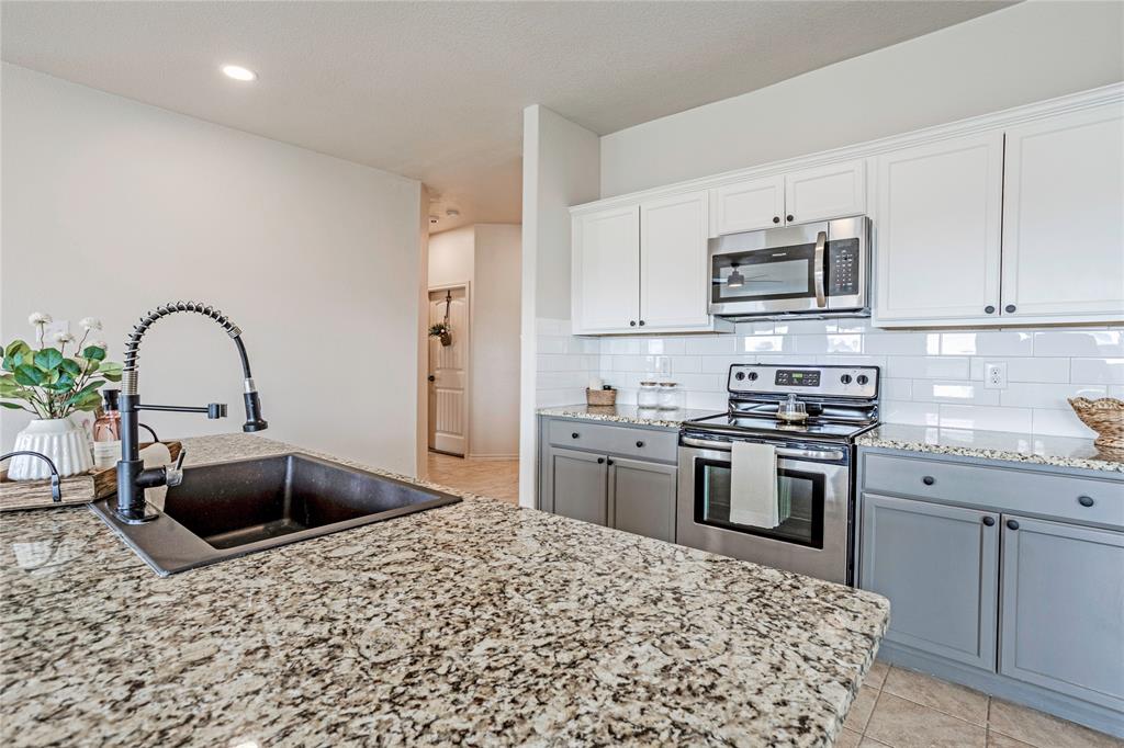 345 Chestnut Lane Ponder, TX 76259 - Photo 5 of 29 a kitchen with stainless steel appliances kitchen island granite countertop a stove a sink and a microwave