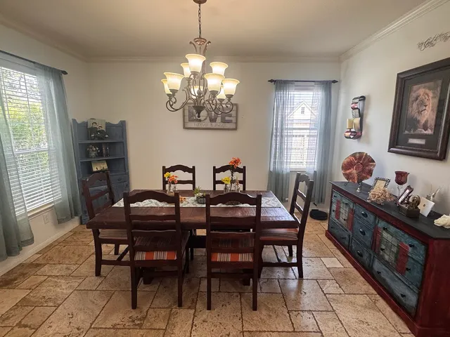a view of a dining room with furniture a chandelier and window