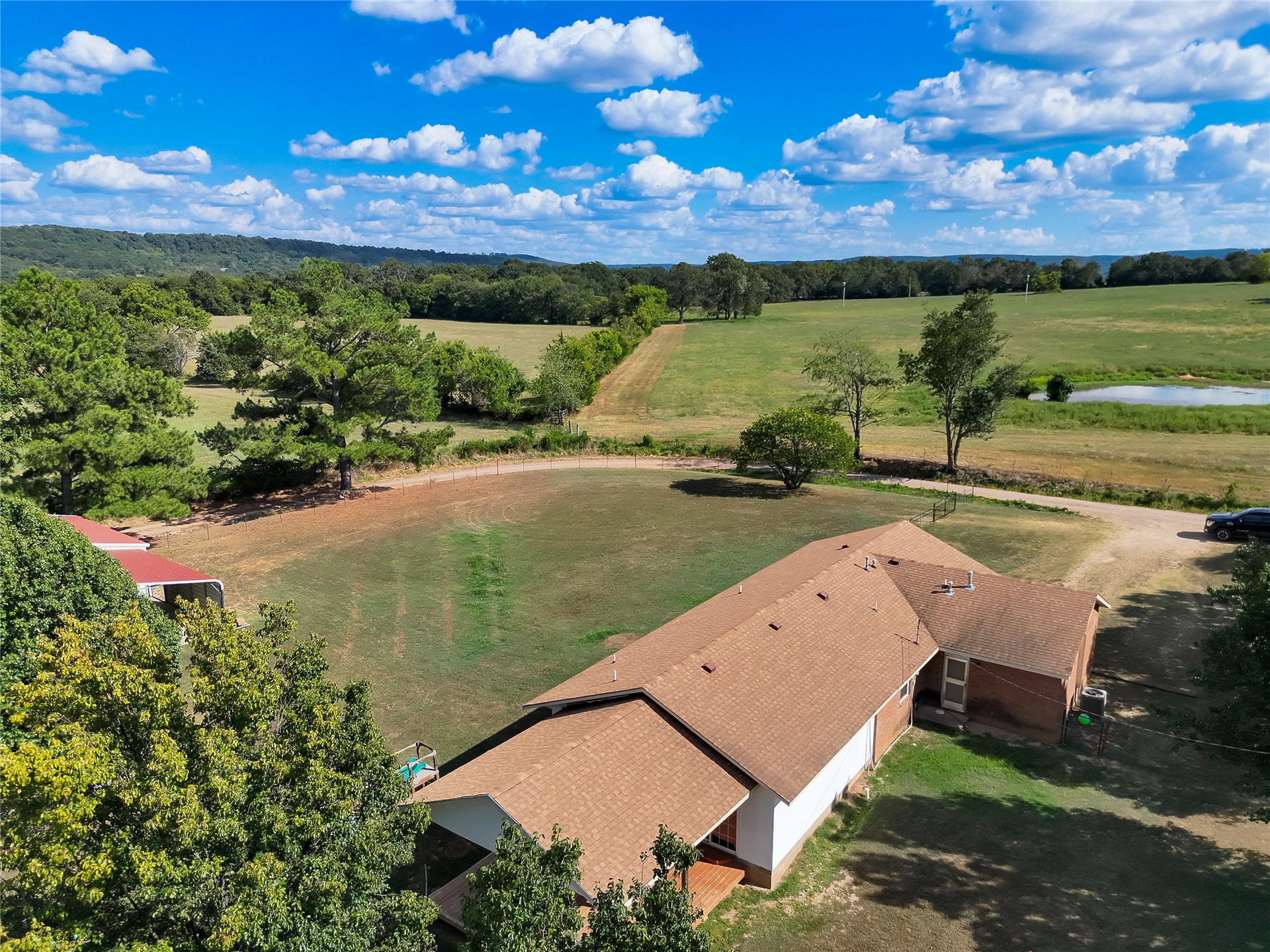 81232 South 4775 Road Stilwell, OK 74960 - Photo 10 of 50 Expansive property featuring a single-story residence with a brown shingle roof and brick siding, surrounded by mature trees and open fields