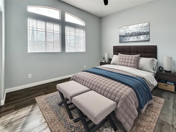 a view of an empty room with wooden floor and a kitchen view