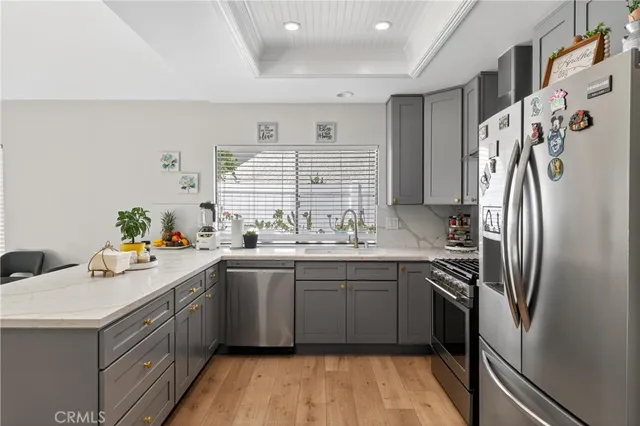 a kitchen with stainless steel appliances a refrigerator a stove a sink dishwasher and a refrigerator with wooden floor