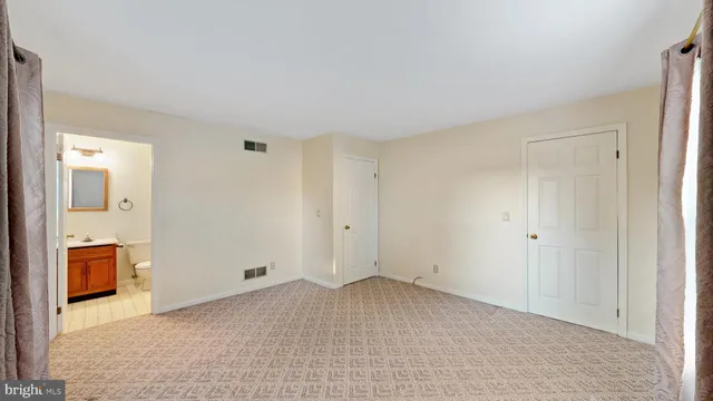 a view of an empty room with window and closet area