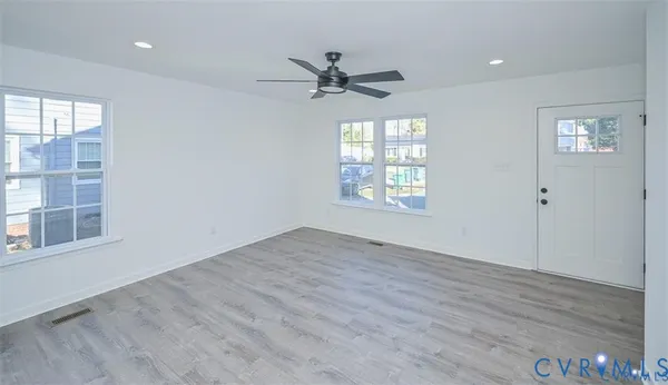 a view of an empty room with a window and wooden floor