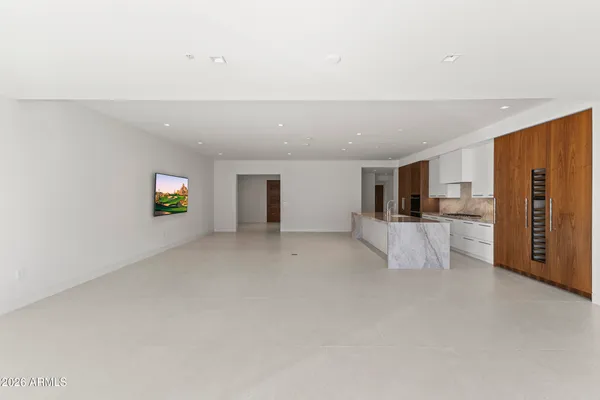 a large white kitchen with kitchen island a large window and a sink