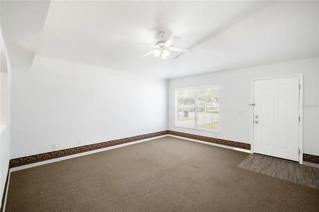 an empty room with a window and a fan
