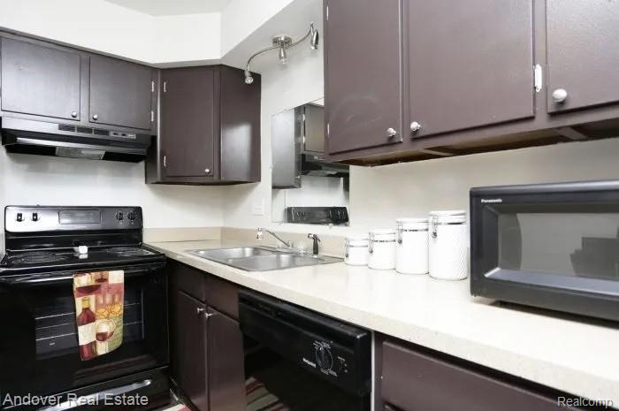 312 South Drake Road Kalamazoo, MI 49009 - Photo 10 of 21 Compact kitchen featuring dark wood-finish cabinetry, light-toned countertops, a stainless steel sink, and a black electric range with an overhead vent