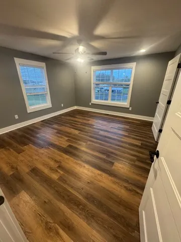 a view of an empty room with window and wooden floor