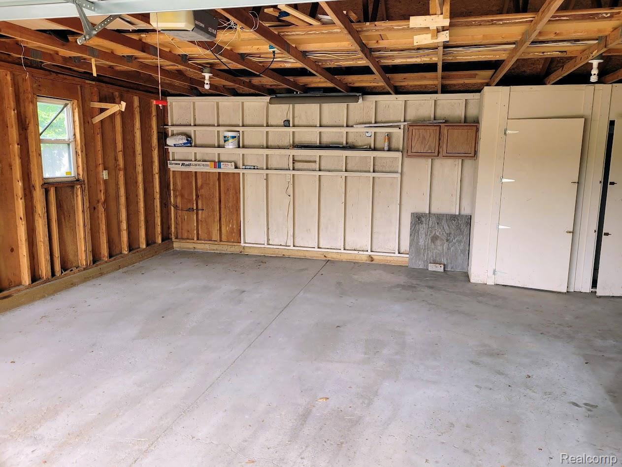 2316 Crescent Lake Road Waterford, MI 48329 - Photo 17 of 17 Spacious garage interior featuring a concrete floor, exposed wood ceiling joists, and built-in shelving