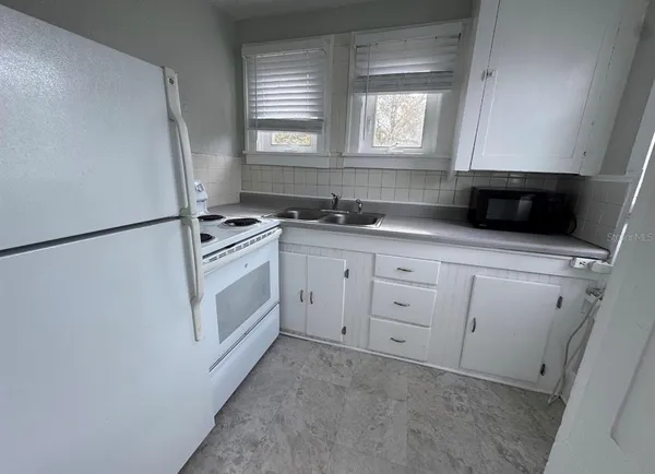 a kitchen with white cabinets and white appliances