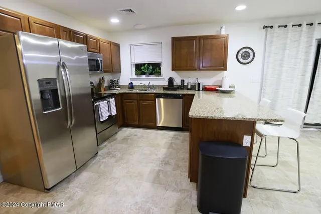 a kitchen with granite countertop a refrigerator and a stove top oven