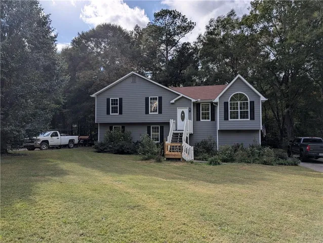 a front view of a house with a garden and trees