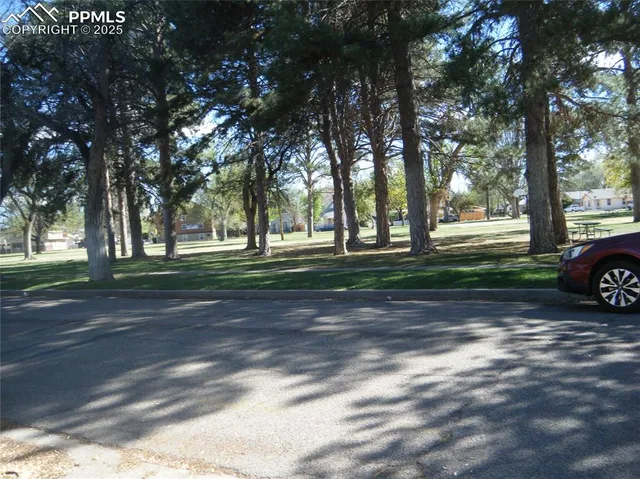 a view of a parked cars in a yard with large trees