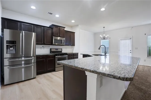 a kitchen with stainless steel appliances granite countertop a sink stove and refrigerator