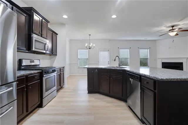 a large kitchen with stainless steel appliances granite countertop a stove a sink dishwasher and a refrigerator with wooden floor