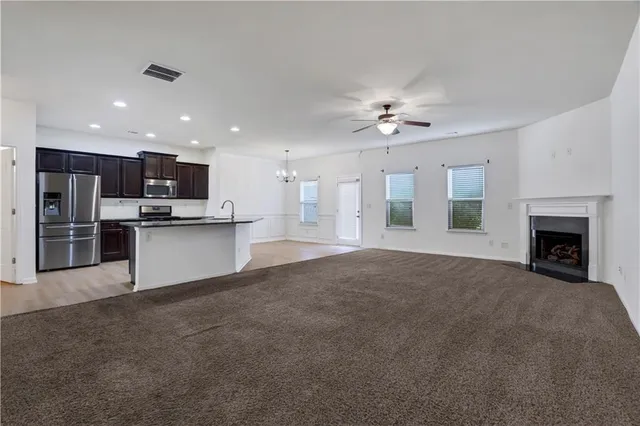 a view of an empty room with kitchen and fireplace