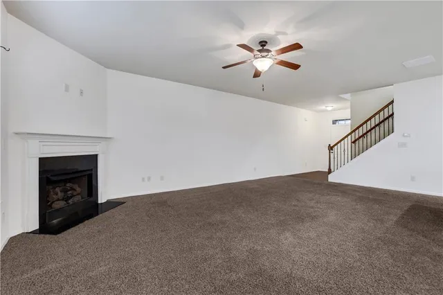 a view of an empty room with chandelier fan and fire place