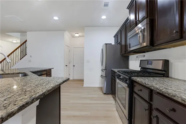 a kitchen with stainless steel appliances granite countertop a sink a stove and a refrigerator