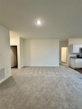a view of an empty room and kitchen with sink