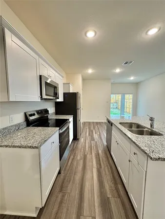 a large kitchen with granite countertop a sink a counter top space appliances and cabinets