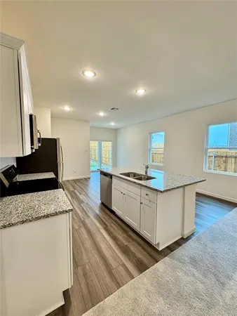 a kitchen with stainless steel appliances granite countertop a sink a stove and a wooden floors
