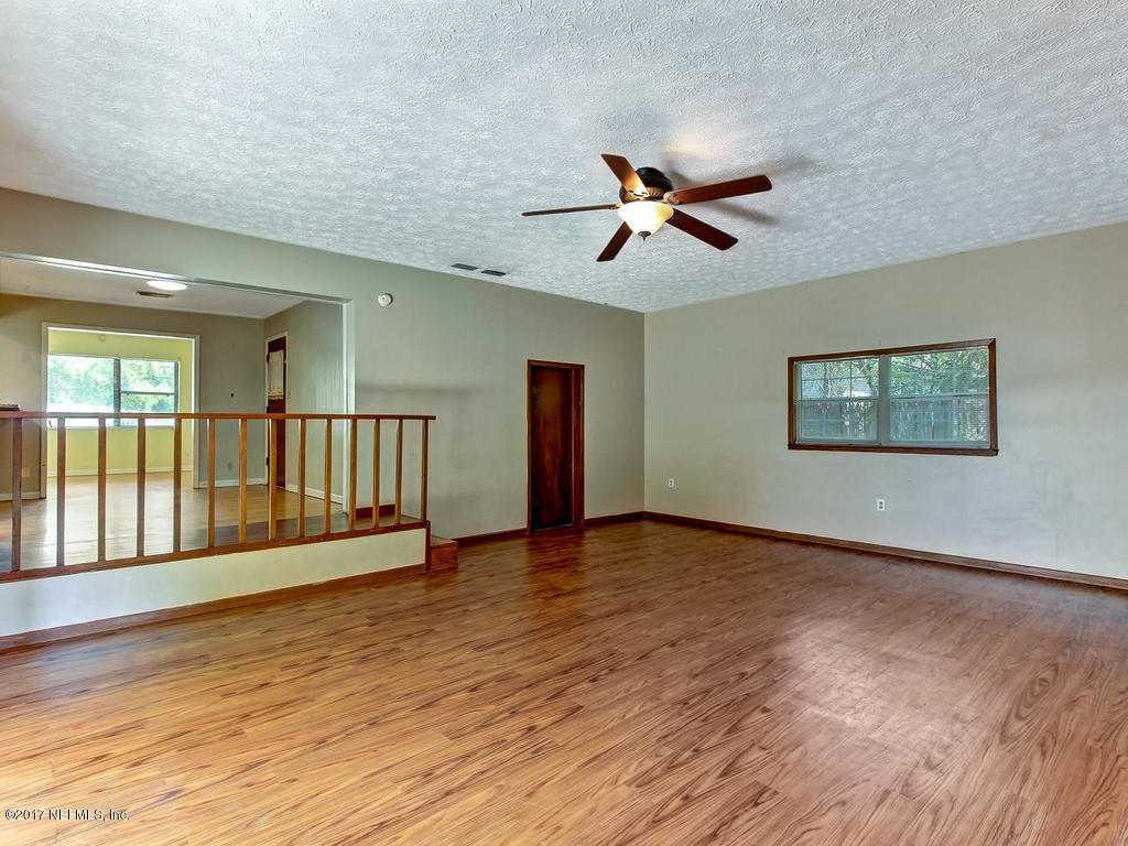 3755 Rogero Road Jacksonville, FL 32277 - Photo 14 of 32 a view of an empty room with wooden floor and a window