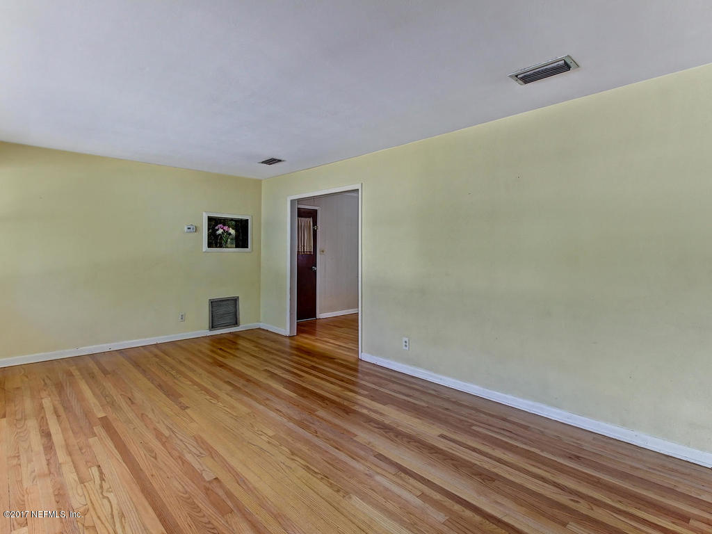3755 Rogero Road Jacksonville, FL 32277 - Photo 3 of 32 a view of an empty room with wooden floor and a window