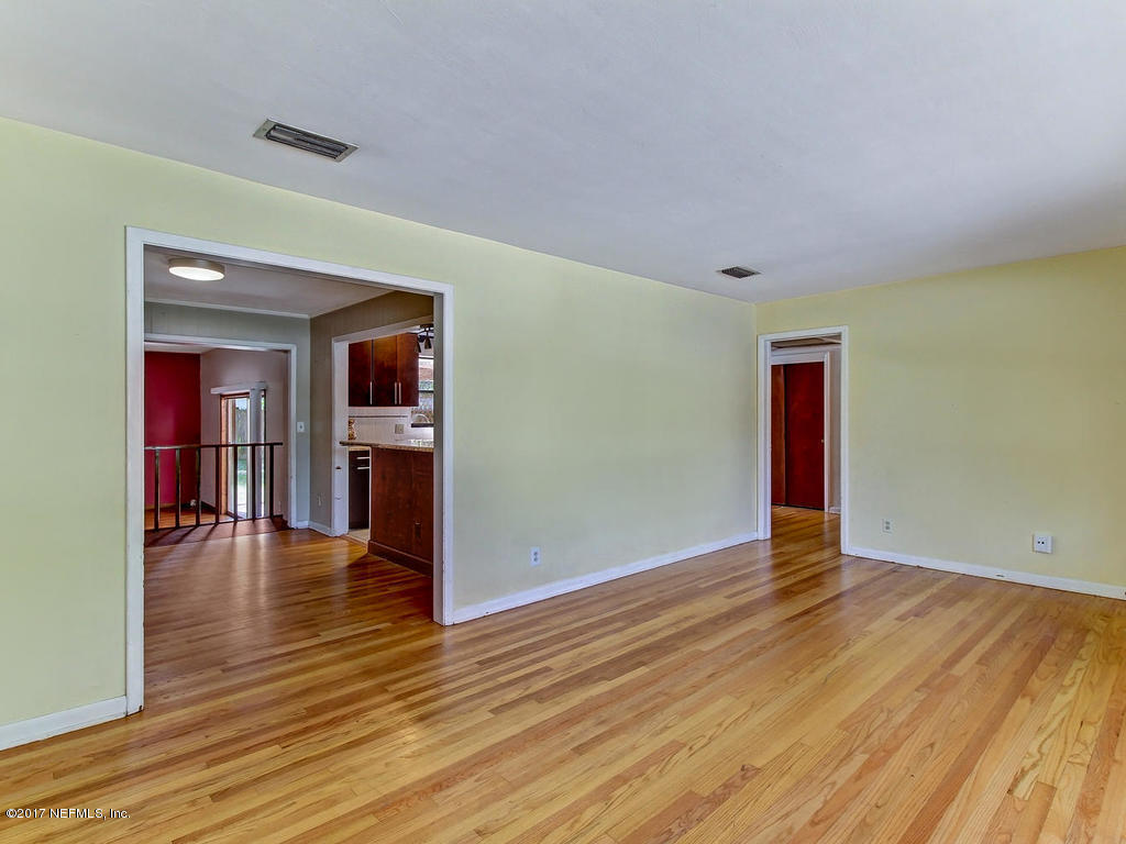 3755 Rogero Road Jacksonville, FL 32277 - Photo 5 of 32 an empty room with wooden floor and a kitchen