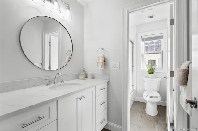 a bathroom with a granite countertop toilet a sink and a mirror