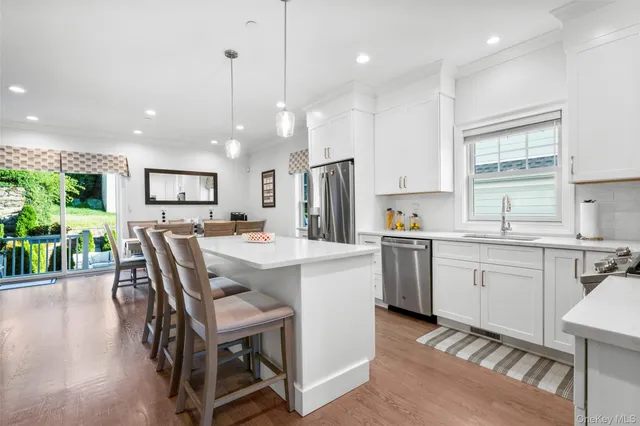 a kitchen with kitchen island granite countertop a sink a stove a refrigerator a dining table and chairs