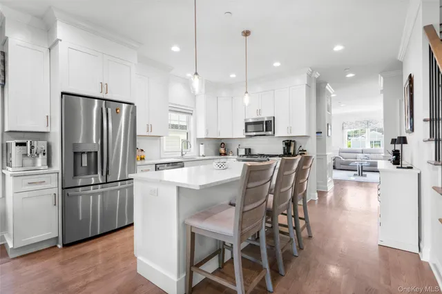 a kitchen with stainless steel appliances kitchen island granite countertop a dining table chairs refrigerator and sink