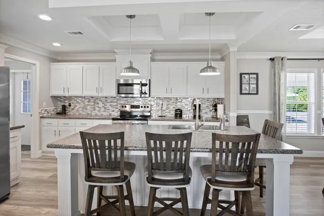 a kitchen with stainless steel appliances kitchen island granite countertop a dining table chairs and a refrigerator