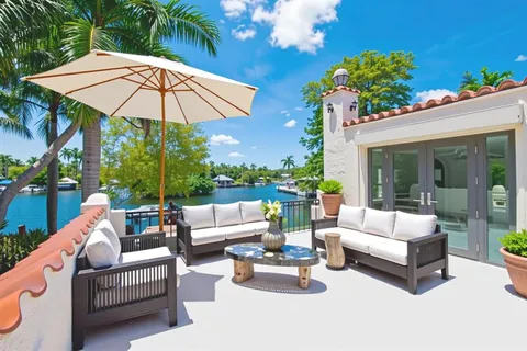 a view of a patio with couches table and chairs under an umbrella