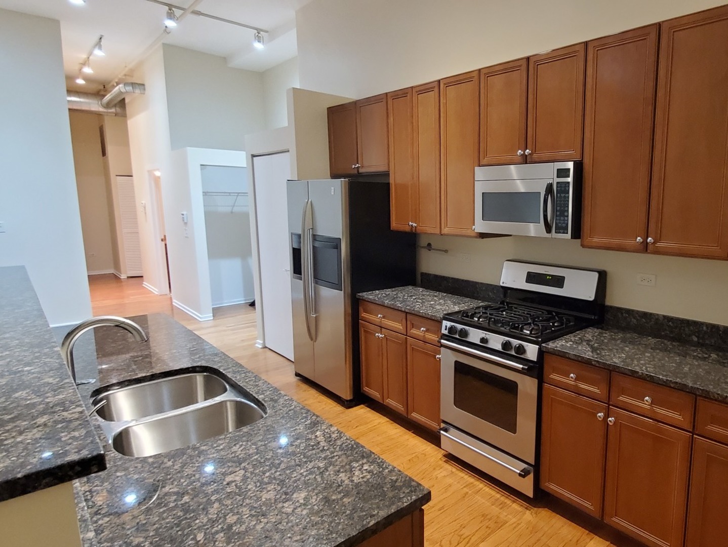 1525 South Sangamon Street, Unit 802P Chicago, IL 60608 - Photo 22 of 32 a kitchen with kitchen island granite countertop wooden cabinets and stainless steel appliances