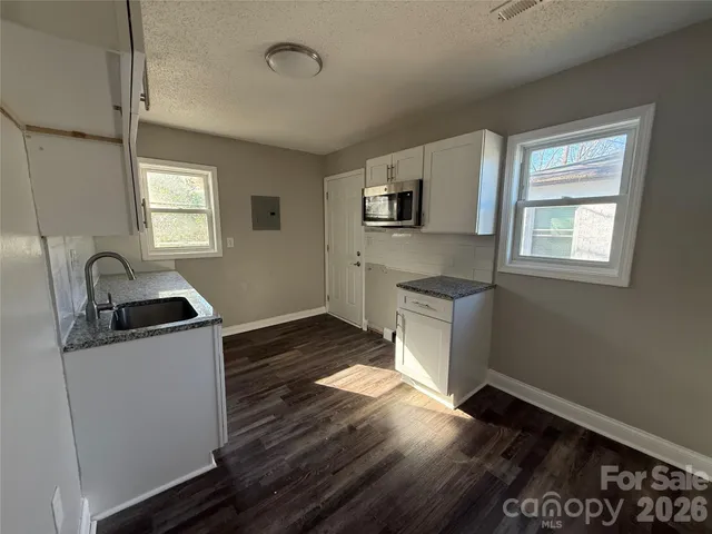 a kitchen with granite countertop a refrigerator and a stove top oven